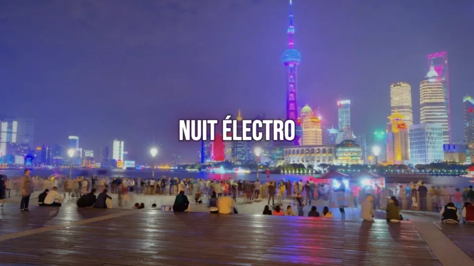 Un vrai paysage animé sur l'écran de la salle : une ville la nuit, des tours illuminées au bord de l'eau, et le nom de la soirée « Nuit Électro » par-dessus